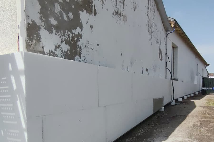Pignon de maison avec enduit tyrolien décollé par plaques et façade noircie, avant isolation par l'extérieur